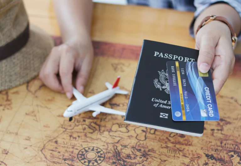 Person holding a passport and credit card over a small toy plane