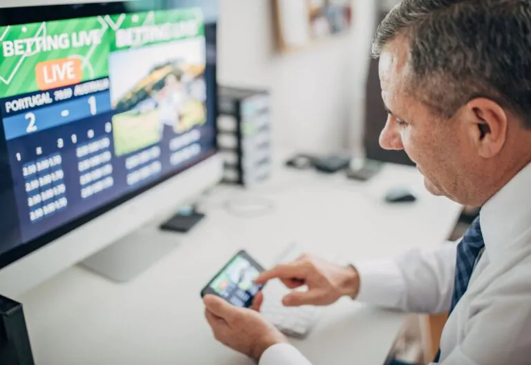 Man sitting at his desk betting on sports on his phone