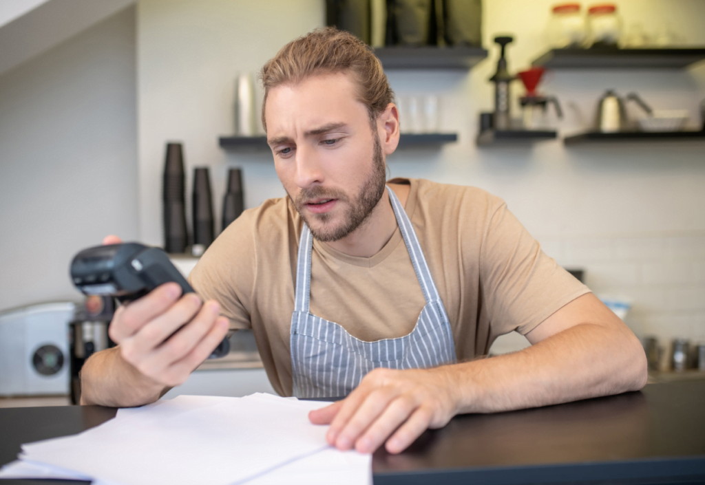 Confused man looking at credit card machine